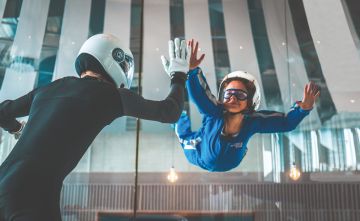 ein Kind und ein Instructor sind zusammen in dem Windkanal in der Jochen Schweizer Arena